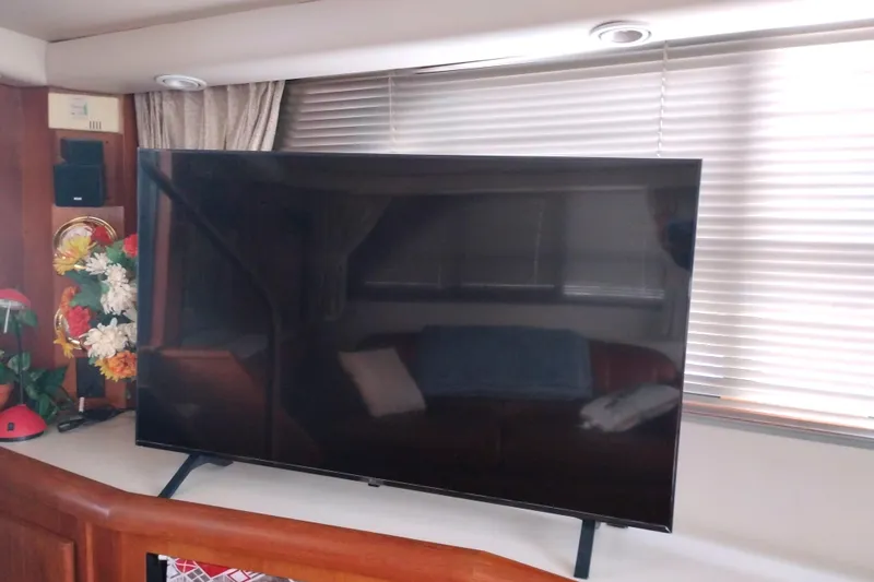 Slide: The Image of Large TV inside 1991 Californian 52 Cockpit Motor Yacht, with flowers and blinds in the background. - 25