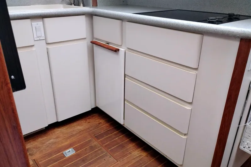 Slide: The Image of 1991 Californian 52 Cockpit Motor Yacht kitchen with white cabinets and wooden flooring. - 31