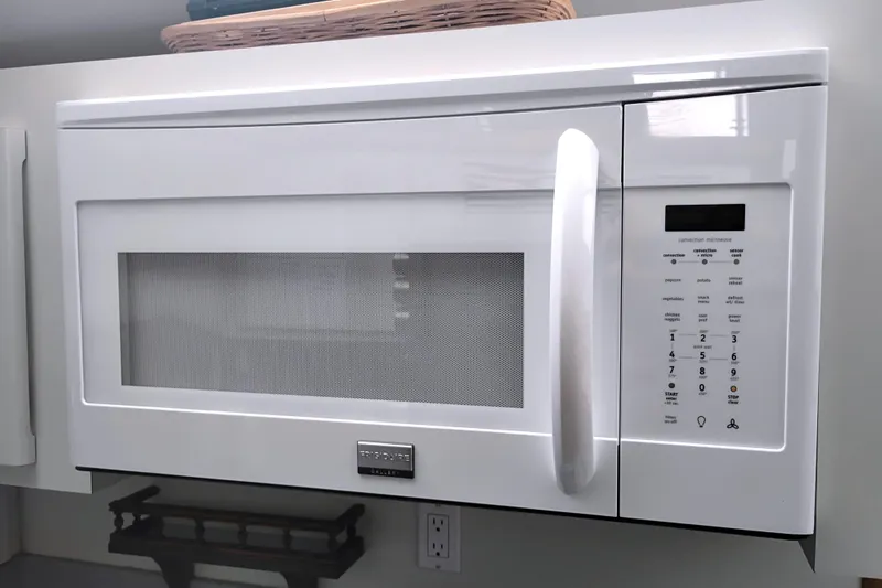 Slide: The Image of White over-the-range microwave with digital controls and handle, mounted in a modern kitchen. - 35