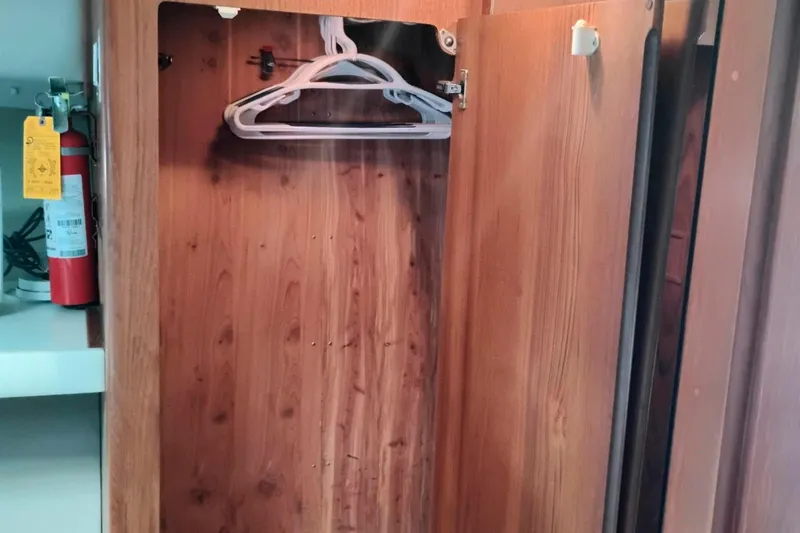 Slide: The Image of Wooden closet interior on 1991 Californian 52 Cockpit Motor Yacht with hangers and fire extinguisher. - 39