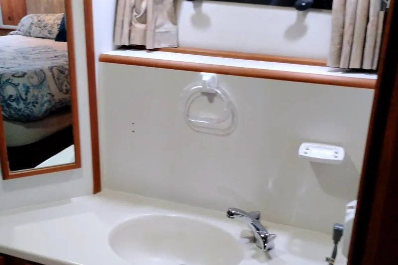 Slide: The Image of Bathroom sink area in a 1991 Californian 52 Cockpit Motor Yacht, featuring a mirror and faucet. - 54