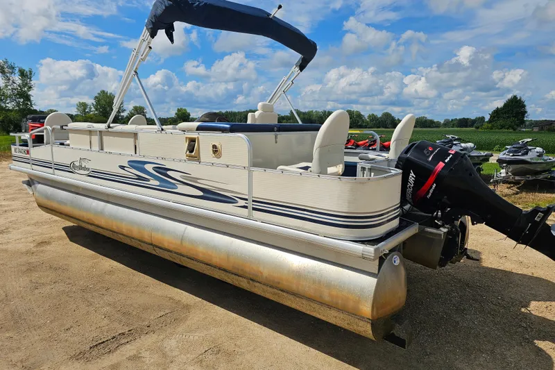 Slide: The Image of 2004 Misty Harbor 2285CF pontoon boat with Mercury outboard motor on sandy terrain. - 3