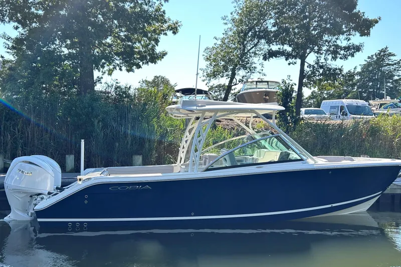The Image of 2026 Cobia 280 Dual Console boat docked, featuring sleek design and powerful outboard engine. - 0