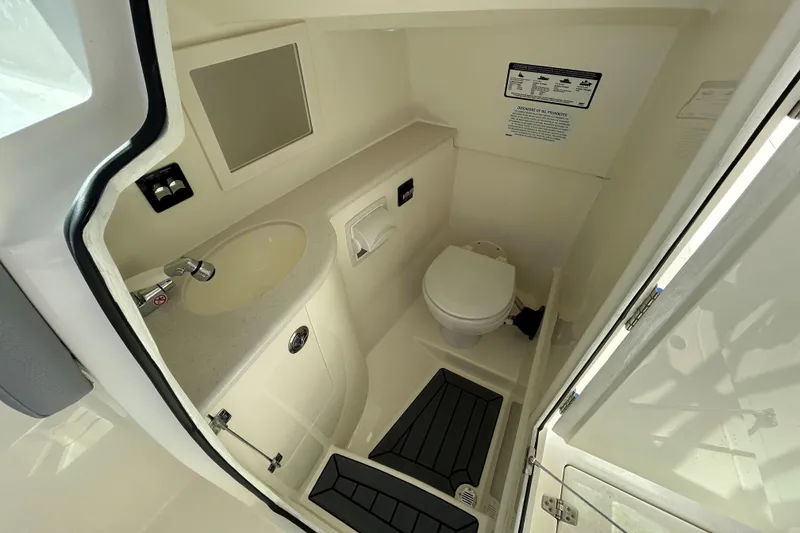 Slide: The Image of 2026 Cobia 280 Dual Console boat bathroom with sink, toilet, and mirror. - 11