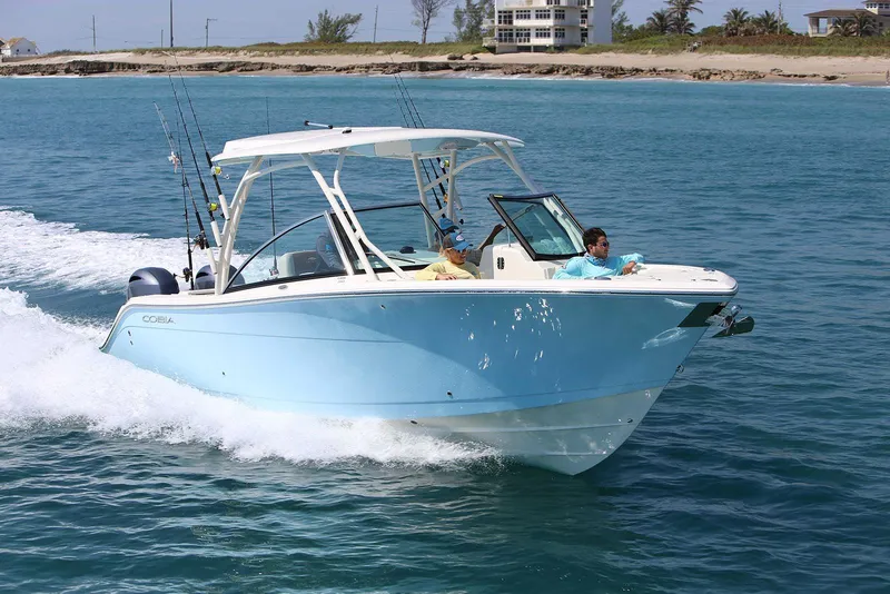 Slide: The Image of 2026 Cobia 280 Dual Console boat cruising on clear blue water. - 19
