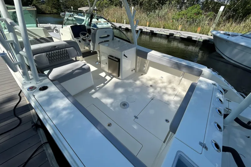 Slide: The Image of 2026 Cobia 280 Dual Console boat interior with seating and storage, docked by a serene waterway. - 3
