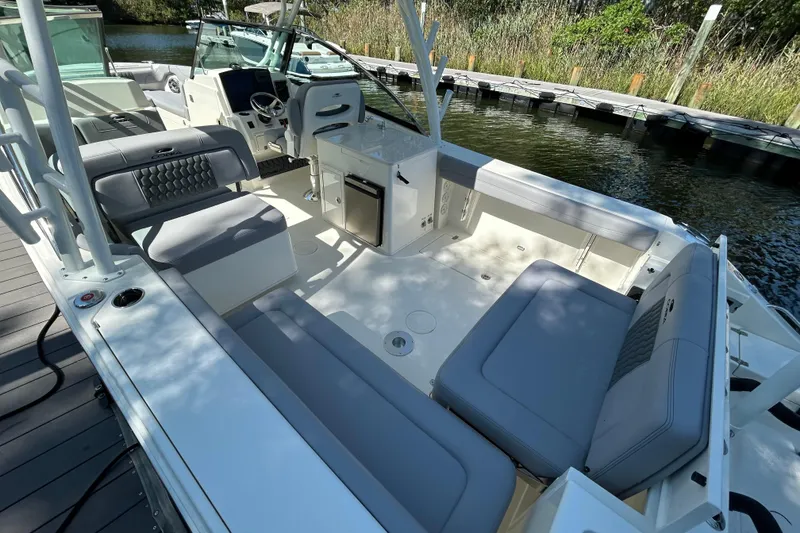 Slide: The Image of 2026 Cobia 280 Dual Console boat interior with seating and helm, docked by water. - 4