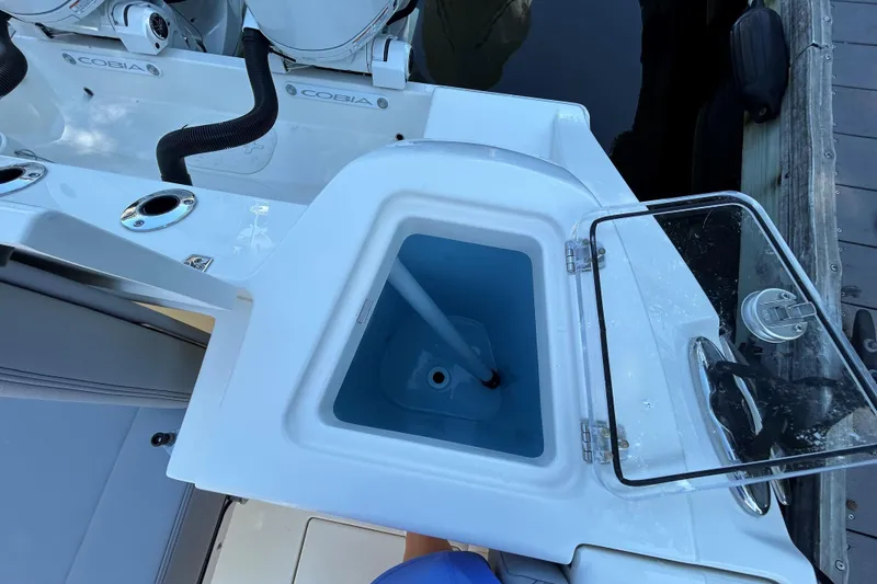 Slide: The Image of 2026 Cobia 280 Dual Console boat with open storage compartment and visible engine parts. - 5