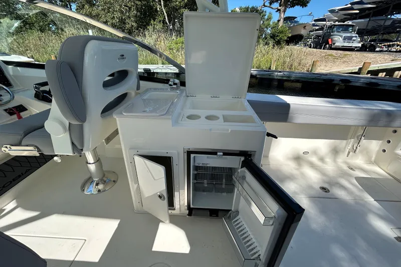 Slide: The Image of 2026 Cobia 280 Dual Console boat interior with open fridge and storage compartments. - 8