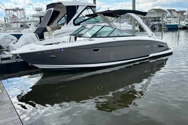 Slide: The Image of 2015 Regal 2800 Bowrider boat docked in a marina, reflecting on calm water. - 20