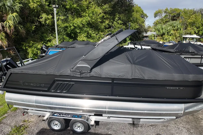Slide: The Image of 2026 Viaggio Diamante 24S pontoon boat covered on trailer, surrounded by greenery. - 28