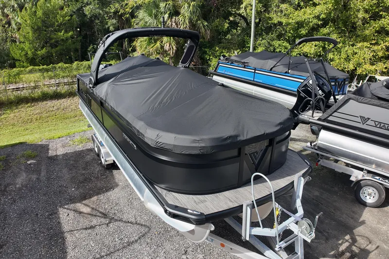 Slide: The Image of 2026 Viaggio Diamante 24S pontoon boat covered, parked on a trailer in a wooded area. - 29