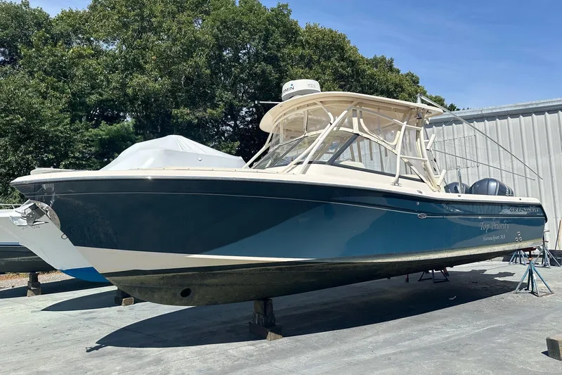 The Image of 2015 Grady-White Freedom 285 boat on stands, outdoors, with trees and building background. - 1