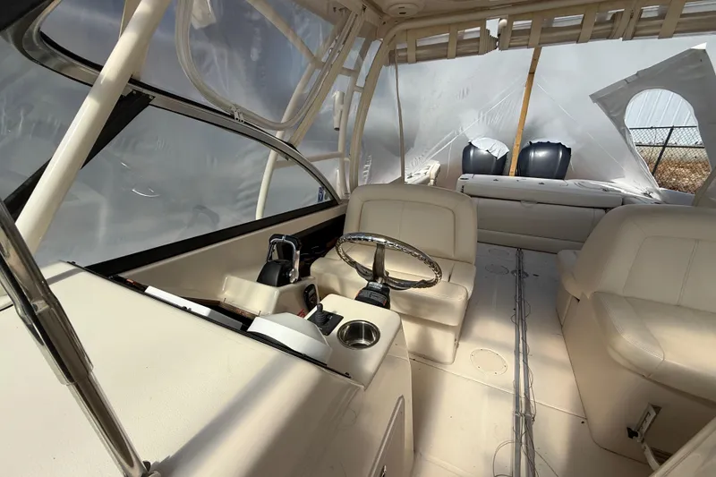 Slide: The Image of Interior of a 2015 Grady-White Freedom 285 boat, featuring steering wheel and seating. - 15