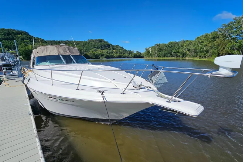 Slide: The Image of 1995 Cruisers Yachts 3775 Esprit docked on a serene river under a clear blue sky. - 4