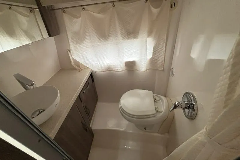 Slide: The Image of 2019 Regal 33 XO boat bathroom with sink, toilet, and curtain. - 14