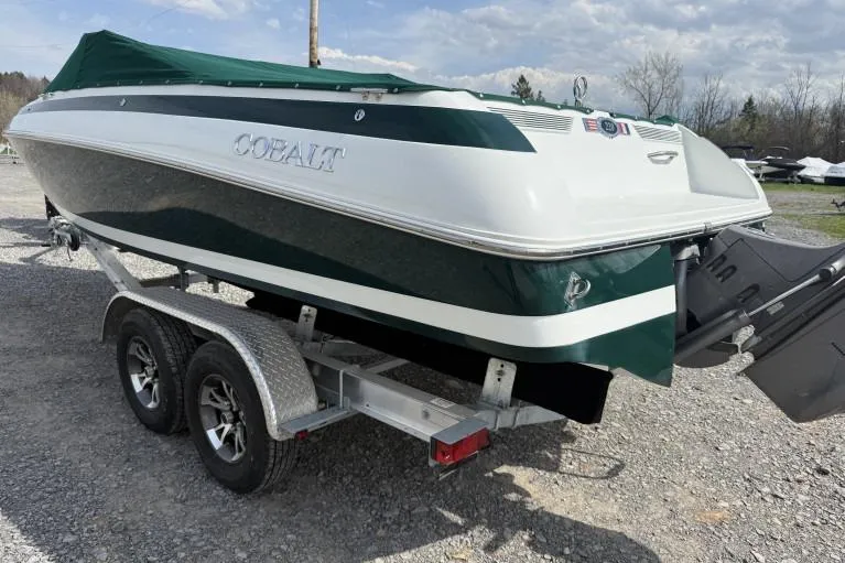 Slide: The Image of 1998 Cobalt 220 boat on trailer, green and white, parked outdoors. - 3