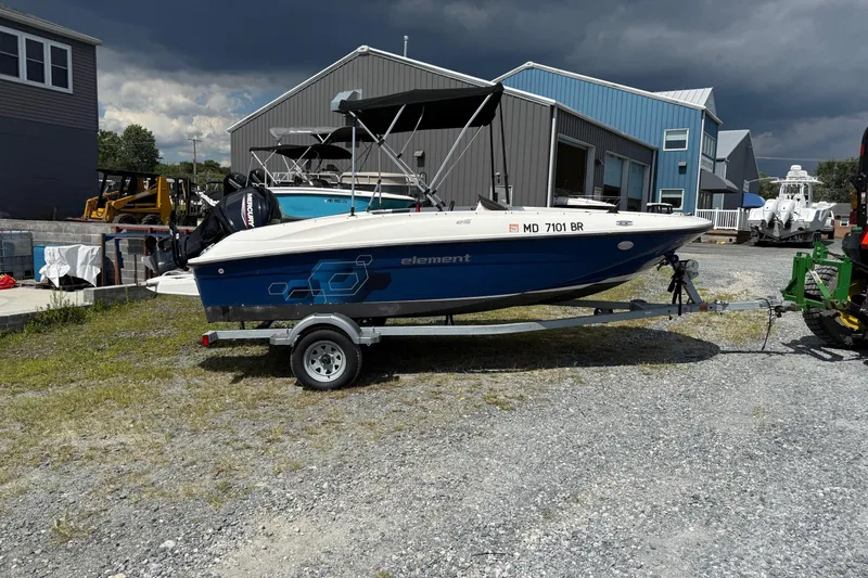 The Image of 2021 Bayliner Element E16 boat on trailer, parked outdoors near industrial buildings. - 0