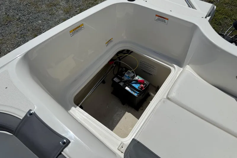 Slide: The Image of 2021 Bayliner Element E16 boat battery compartment with visible wiring and storage area. - 11