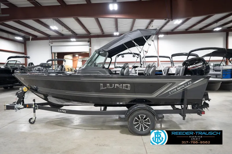 Slide: The Image of 2026 Lund 1775 Impact XS boat in showroom with trailer and Mercury engine. - 11