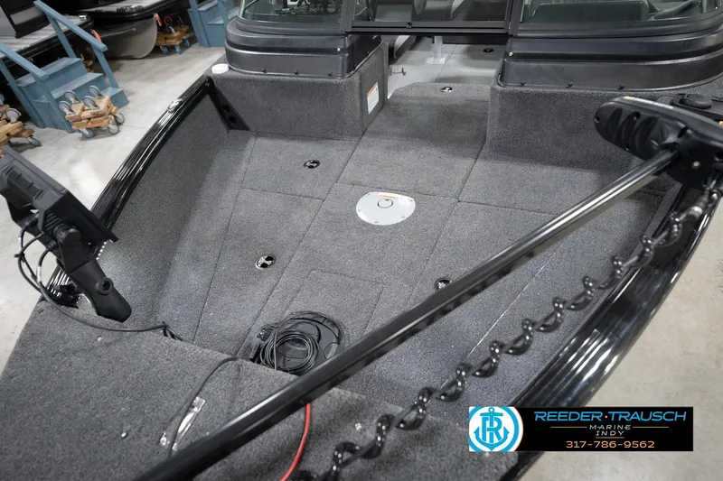 Slide: The Image of 2026 Lund 1775 Impact XS boat interior with carpeted deck and fishing equipment. - 12