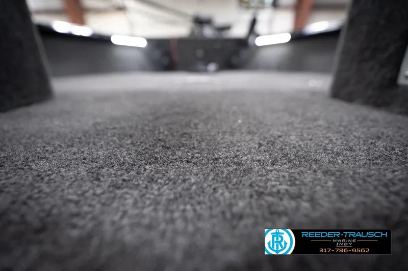 Slide: The Image of 2026 Lund 1775 Impact XS boat interior with carpeted flooring, Reeder-Trausch Marine logo visible. - 51