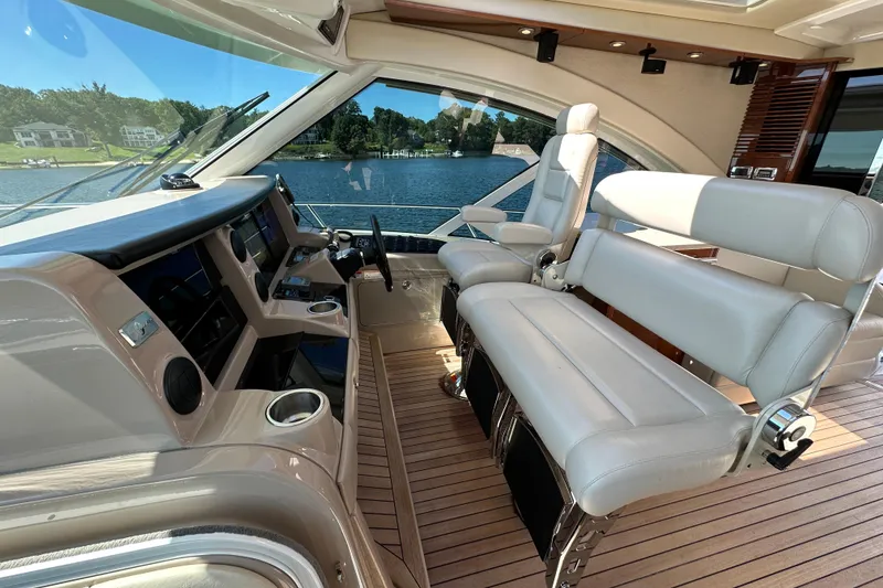 Slide: The Image of 2009 Sea Ray 60 Sundancer helm with luxurious seating and modern controls, overlooking serene waters. - 14