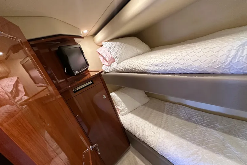 Slide: The Image of 2009 Sea Ray 60 Sundancer cabin with bunk beds and TV, featuring elegant wood finish. - 35