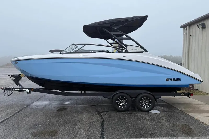 Slide: The Image of 2026 Yamaha Boats 252SD in blue on trailer, parked outdoors. - 4