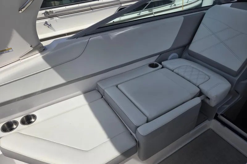 Slide: The Image of 2021 Regal 26 Express boat interior with white cushioned seating and cup holders. - 12