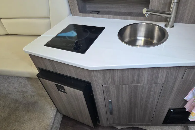 Slide: The Image of 2021 Regal 26 Express boat kitchenette with stove, sink, and mini fridge. - 16