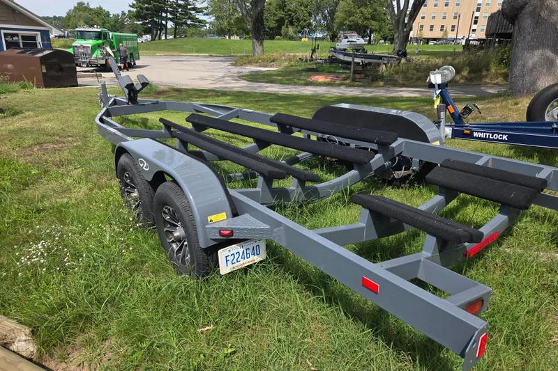 Slide: The Image of Trailer for 2021 Regal 26 Express boat on grassy area, with trees and buildings in background. - 38