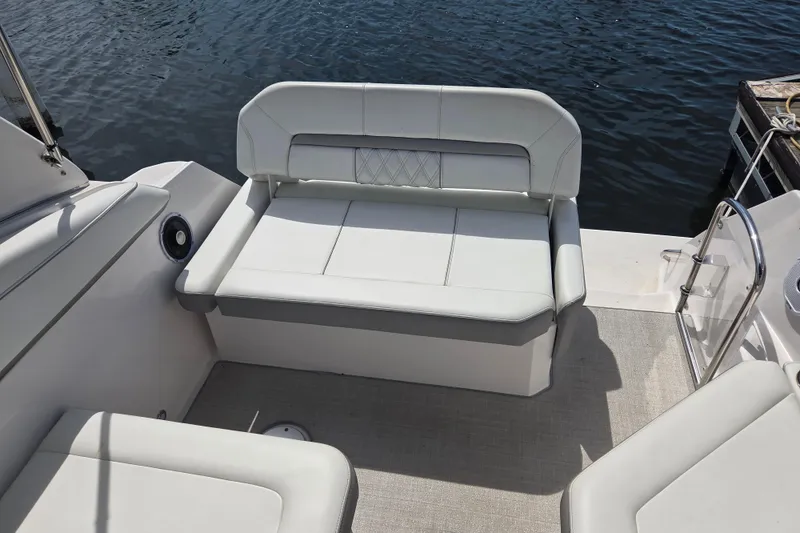 Slide: The Image of 2021 Regal 26 Express boat interior with white cushioned seating by the water. - 9