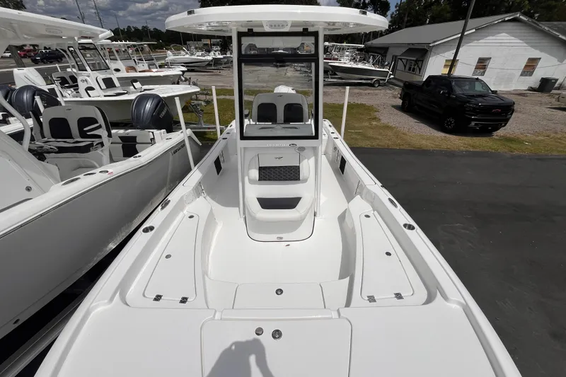 Slide: The Image of 2026 Tidewater 2210 Carolina Bay boat, white interior, docked with other boats and a truck nearby. - 12