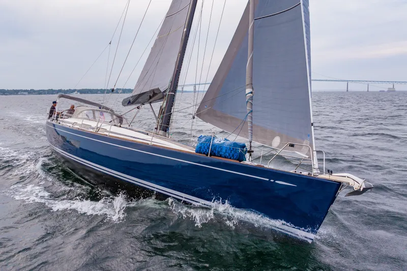 Slide: The Image of 2018 Nautor Swan 54 sailing yacht on open water with bridge in background. - 2