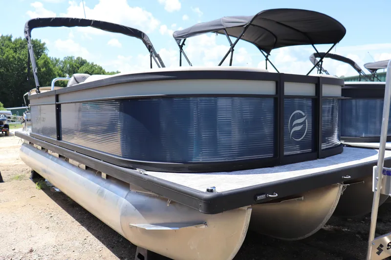 Slide: The Image of 2025 Flagship Freedom 22 CU Tritoon boat with canopy, parked on land. - 0