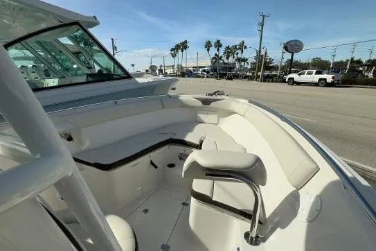 Slide: The Image of 2024 Sailfish 242 CC boat interior with seating, parked near a road under a clear sky. - 23