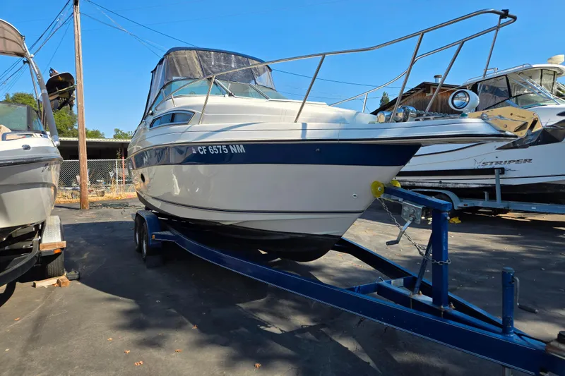 Slide: The Image of 1995 Regal Commodore 258 boat on trailer, parked outdoors under clear blue sky. - 2