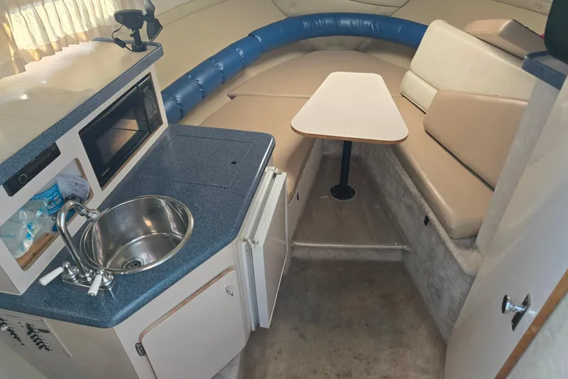 Slide: The Image of 1995 Regal Commodore 258 boat interior with kitchenette, sink, microwave, and seating area. - 5