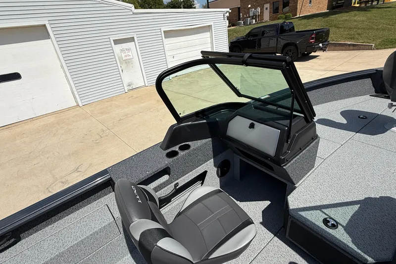 Slide: The Image of 2025 Lund 2075 Impact XS boat interior with seating and windshield, parked near garages. - 22