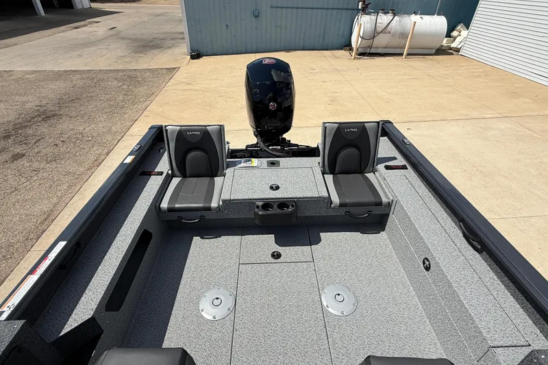 Slide: The Image of 2025 Lund 2075 Impact XS boat interior with two seats and motor, docked outdoors. - 25