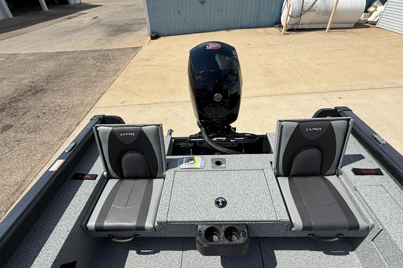 Slide: The Image of 2025 Lund 2075 Impact XS boat interior with seating and motor, docked outdoors. - 26