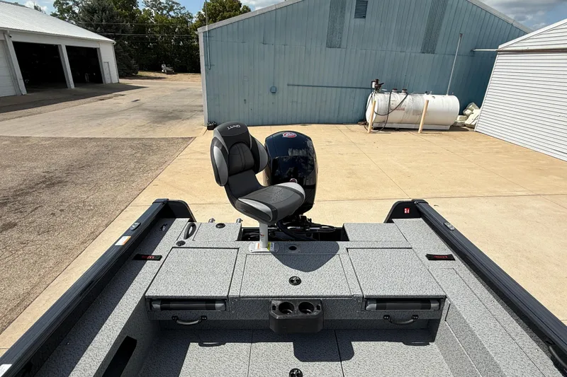 Slide: The Image of 2025 Lund 2075 Impact XS boat with seating and storage, parked outdoors. - 32