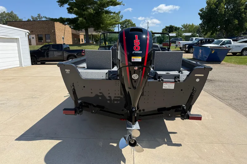 Slide: The Image of 2025 Lund 2075 Impact XS boat with powerful 150 HP outboard motor, parked outdoors. - 6