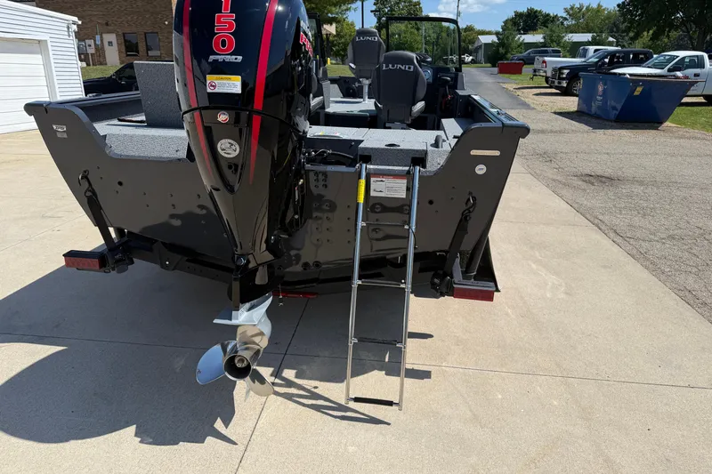 Slide: The Image of 2025 Lund 2075 Impact XS boat with outboard motor and ladder on a driveway. - 8