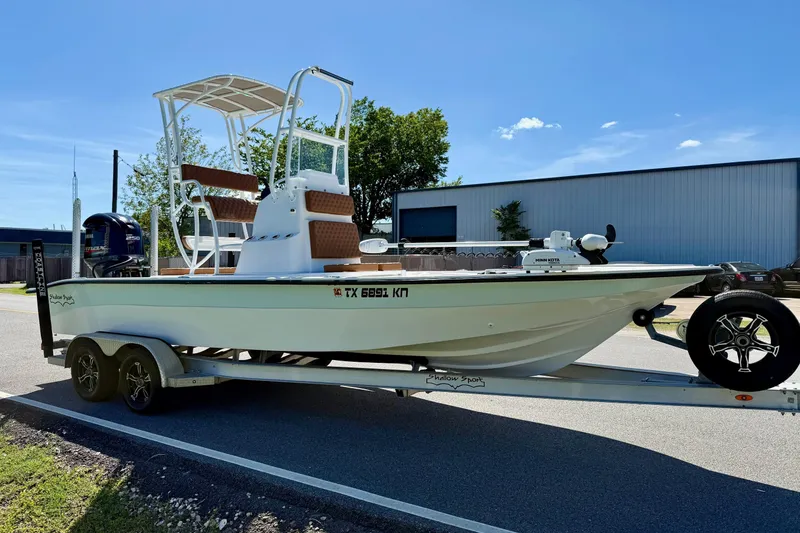 Slide: The Image of 2022 Shallow Sport 24 Modified V boat on trailer, parked outdoors under clear sky. - 5