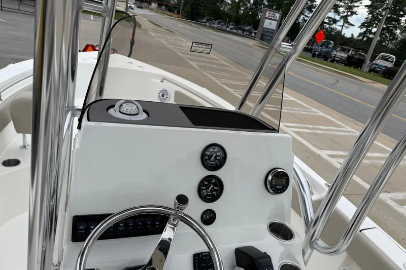 Slide: The Image of 2026 Key West 203 FS boat dashboard with steering wheel and gauges, parked near a road. - 20