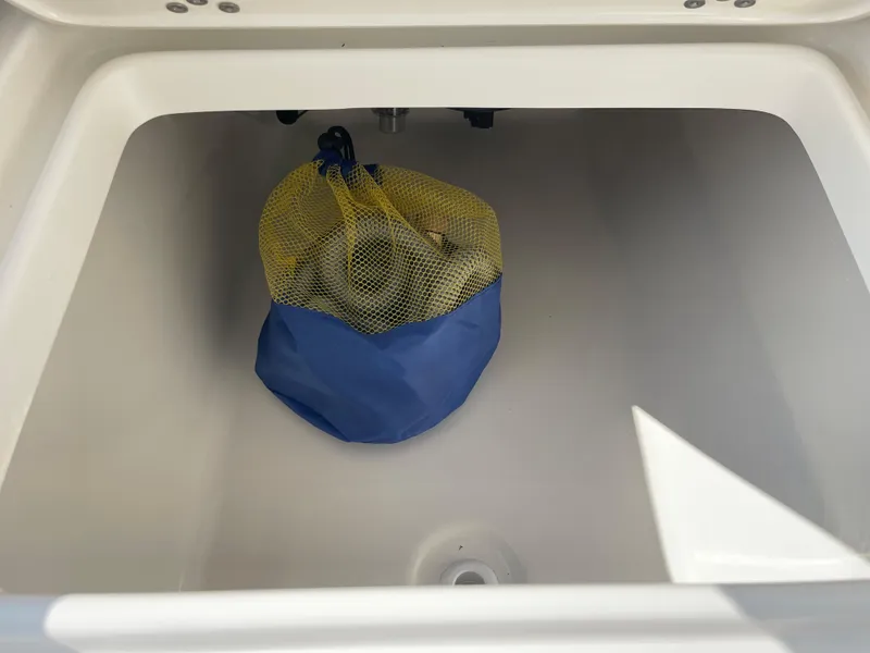 Slide: The Image of Key West 203 FS 2025 boat storage compartment with blue and yellow mesh bag. - 27