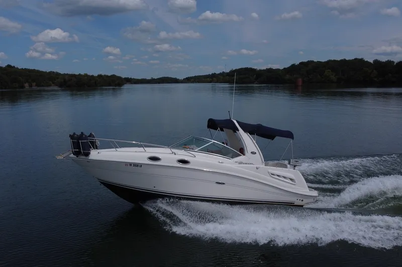 Slide: The Image of 2006 Sea Ray 260 Sundancer cruising on a serene lake under a partly cloudy sky. - 3