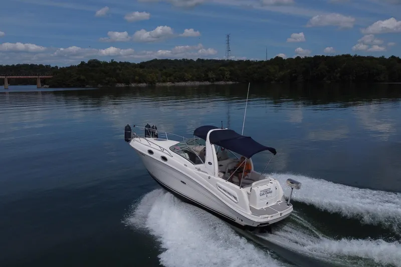 Slide: The Image of 2006 Sea Ray 260 Sundancer cruising on a serene lake under a blue sky. - 4